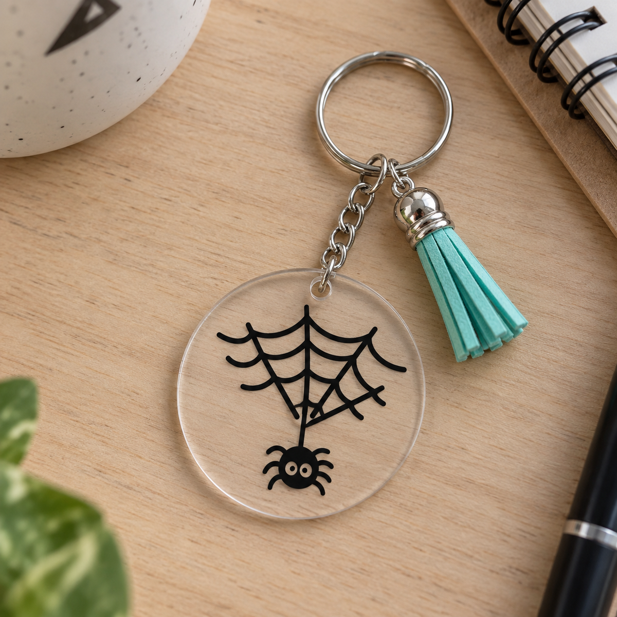 Porte-clés Halloween acrylique transparent araignée suspendue à sa toile avec pompon vert menthe